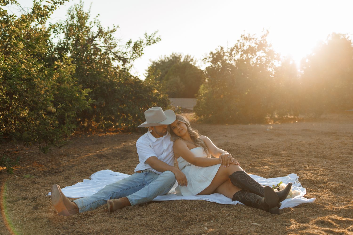 Family lounging together in a grassy field during golden hour sunset.