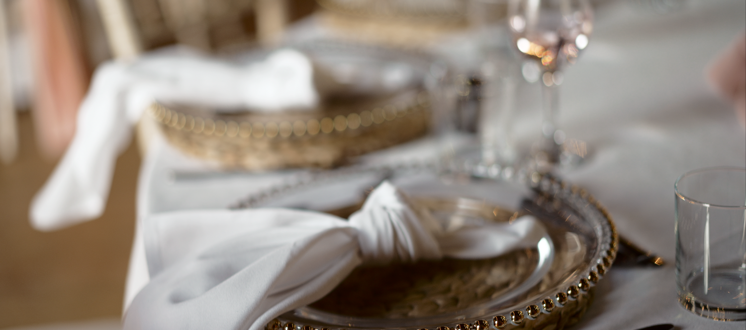 Elegant place setting with silver charger plate and wine glass.