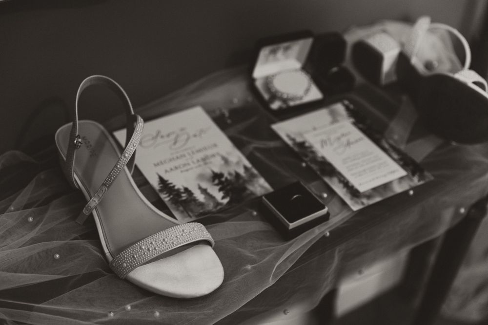Black and white photo of wedding accessories including invitations and sandals.