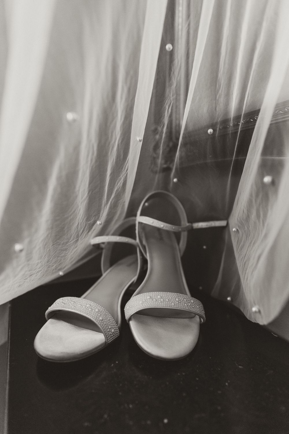 Elegant bridal sandals with sparkly straps against flowing white fabric.
