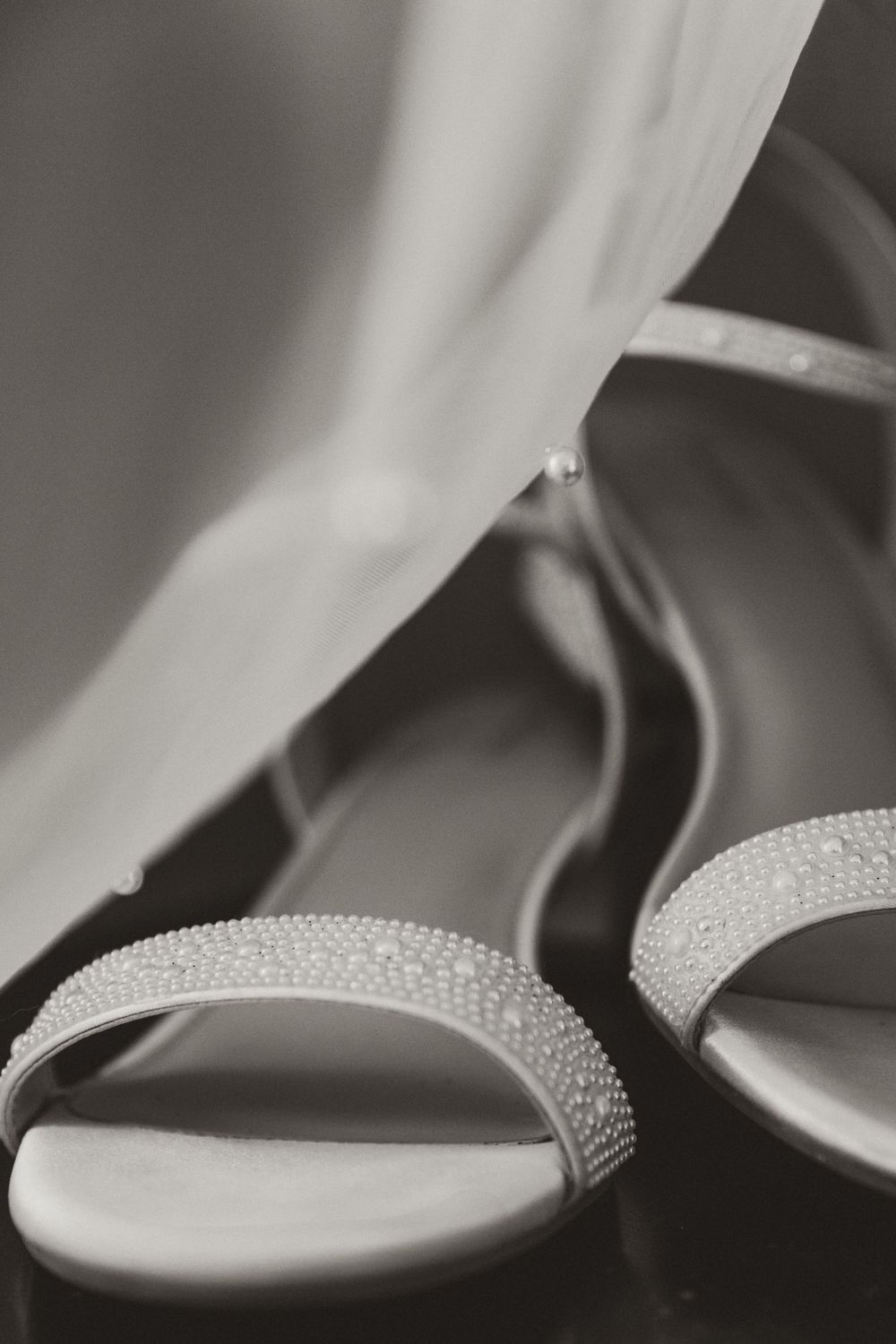 Close-up black and white photo of rhinestone-embellished bridal sandals.