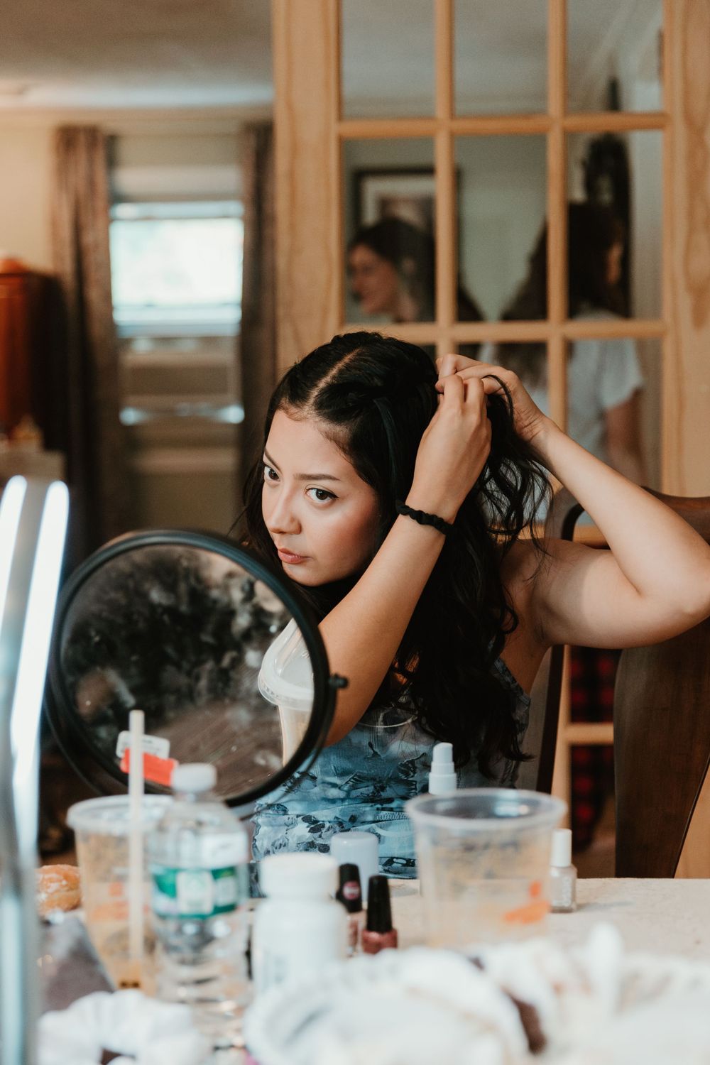Wedding preparation scene reflected in mirror showing hair and makeup styling.