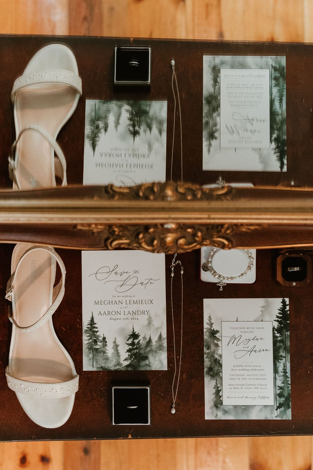 Wedding invitation suite with forest theme alongside bridal shoes and ring boxes on wooden surface.