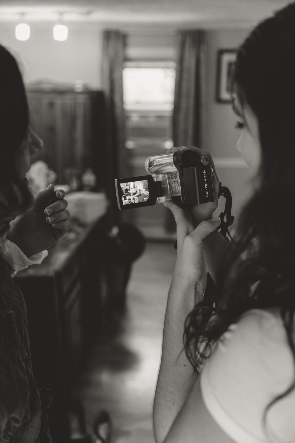Person filming with handheld camera in dimly lit indoor setting.