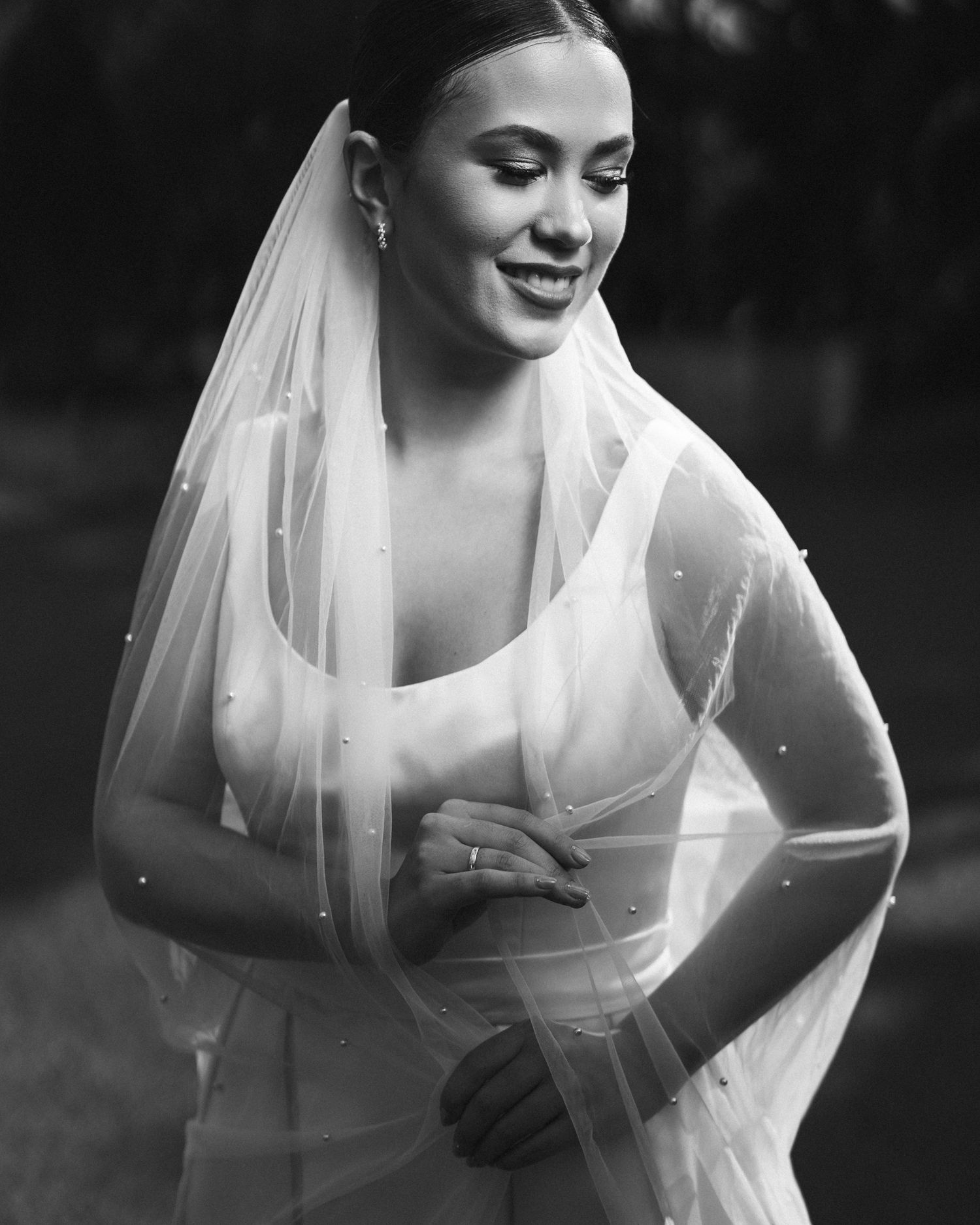 A black and white bridal portrait with a sheer veil creating an ethereal effect.