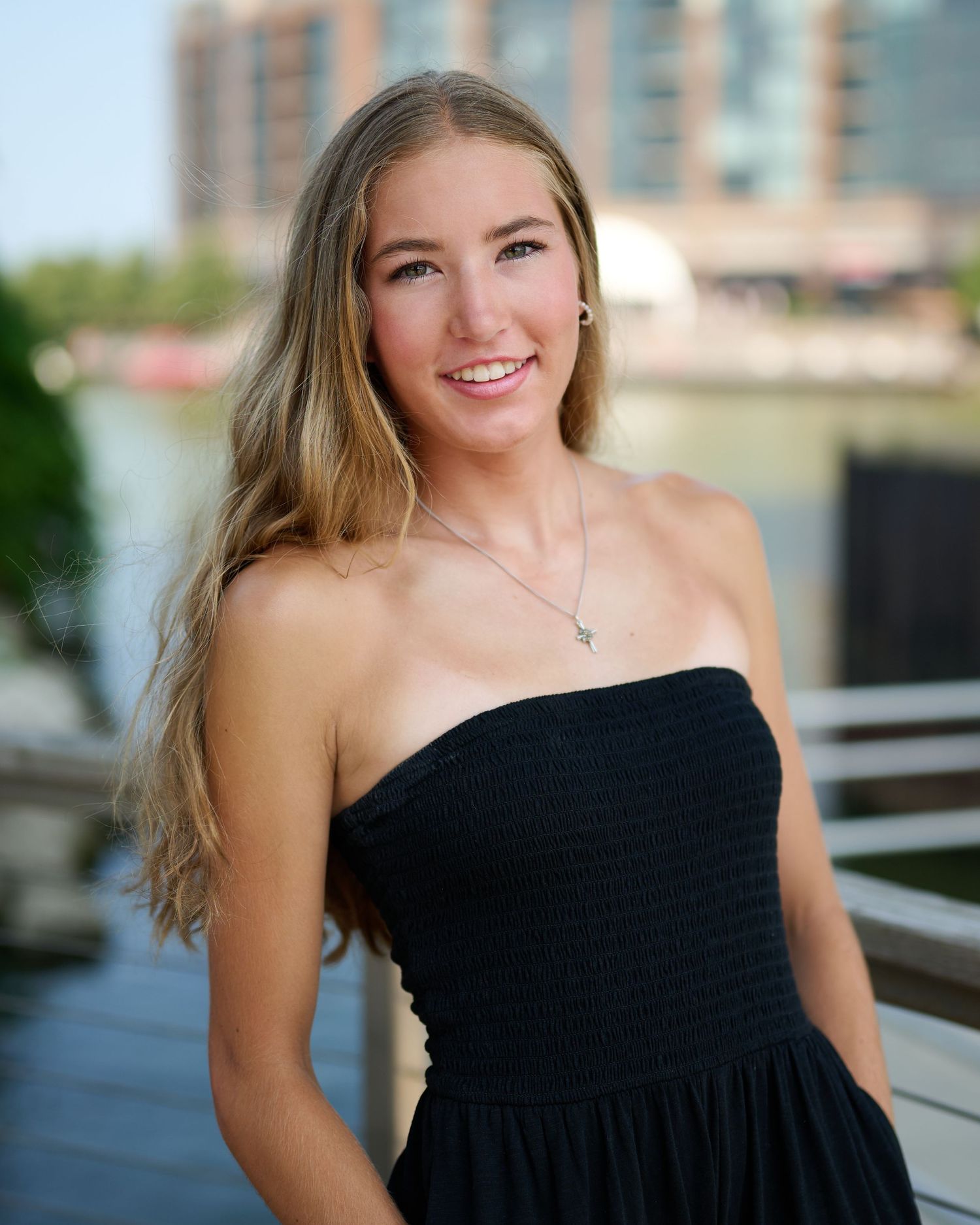 A series of portrait photos showing someone in a black strapless dress against an urban backdrop.