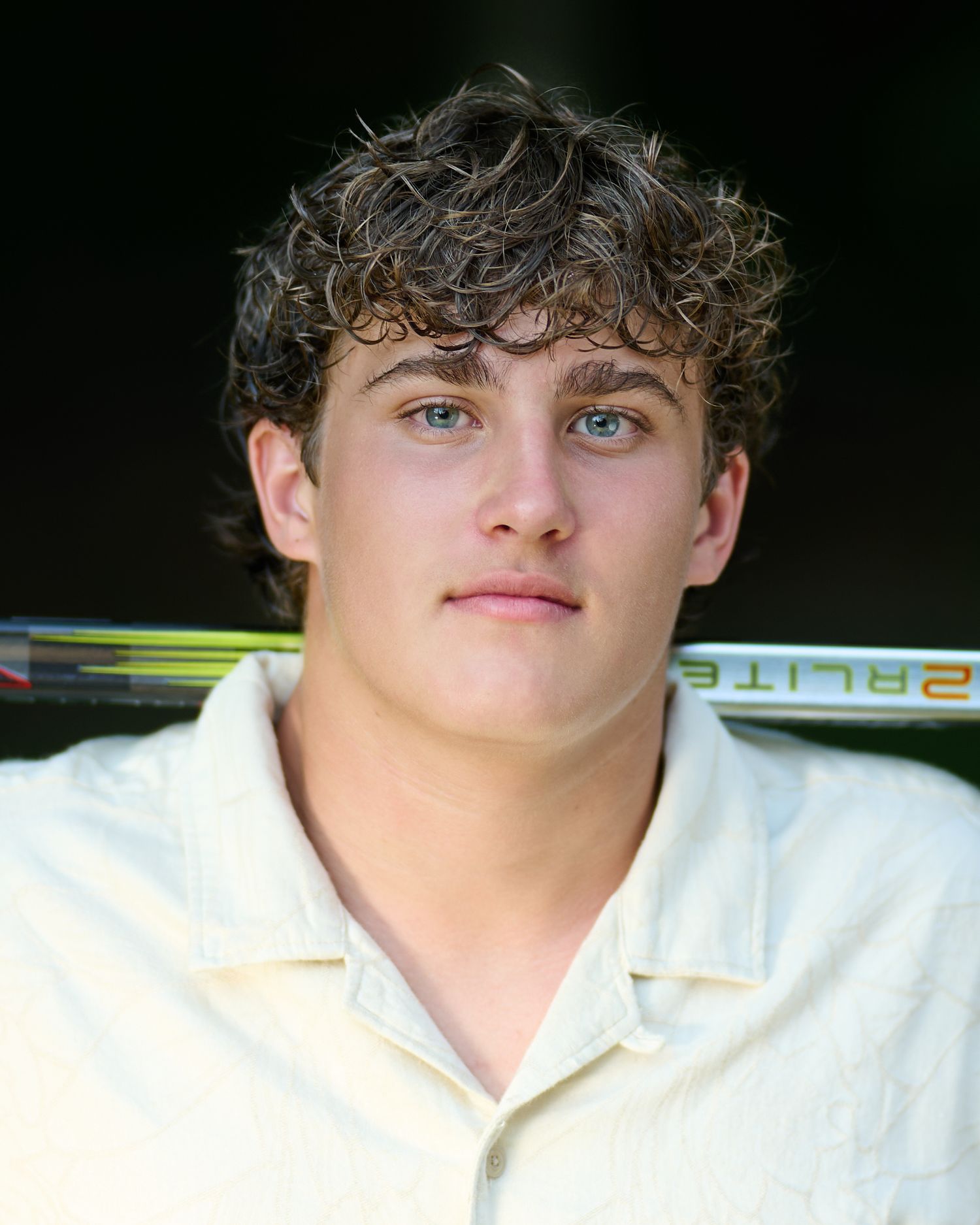 A person in a white shirt with curly dark hair photographed from different angles against a dark background.