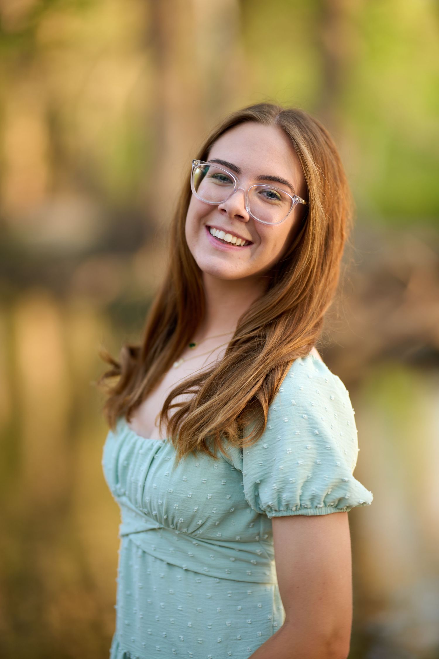 Portrait in natural light showing a mint green dress and warm smile outdoors.