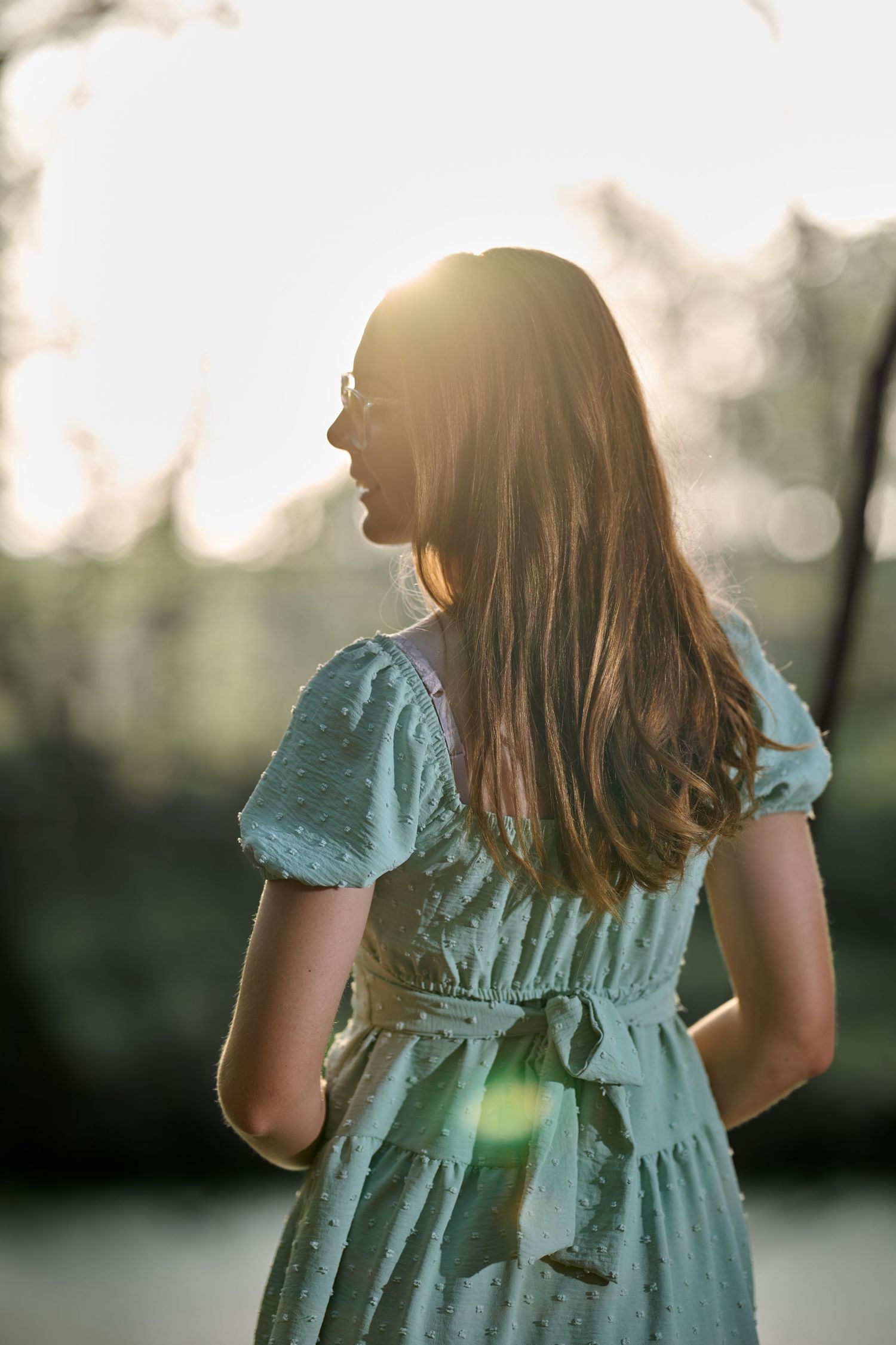 Back view of someone in a mint green dress with puff sleeves during golden hour.