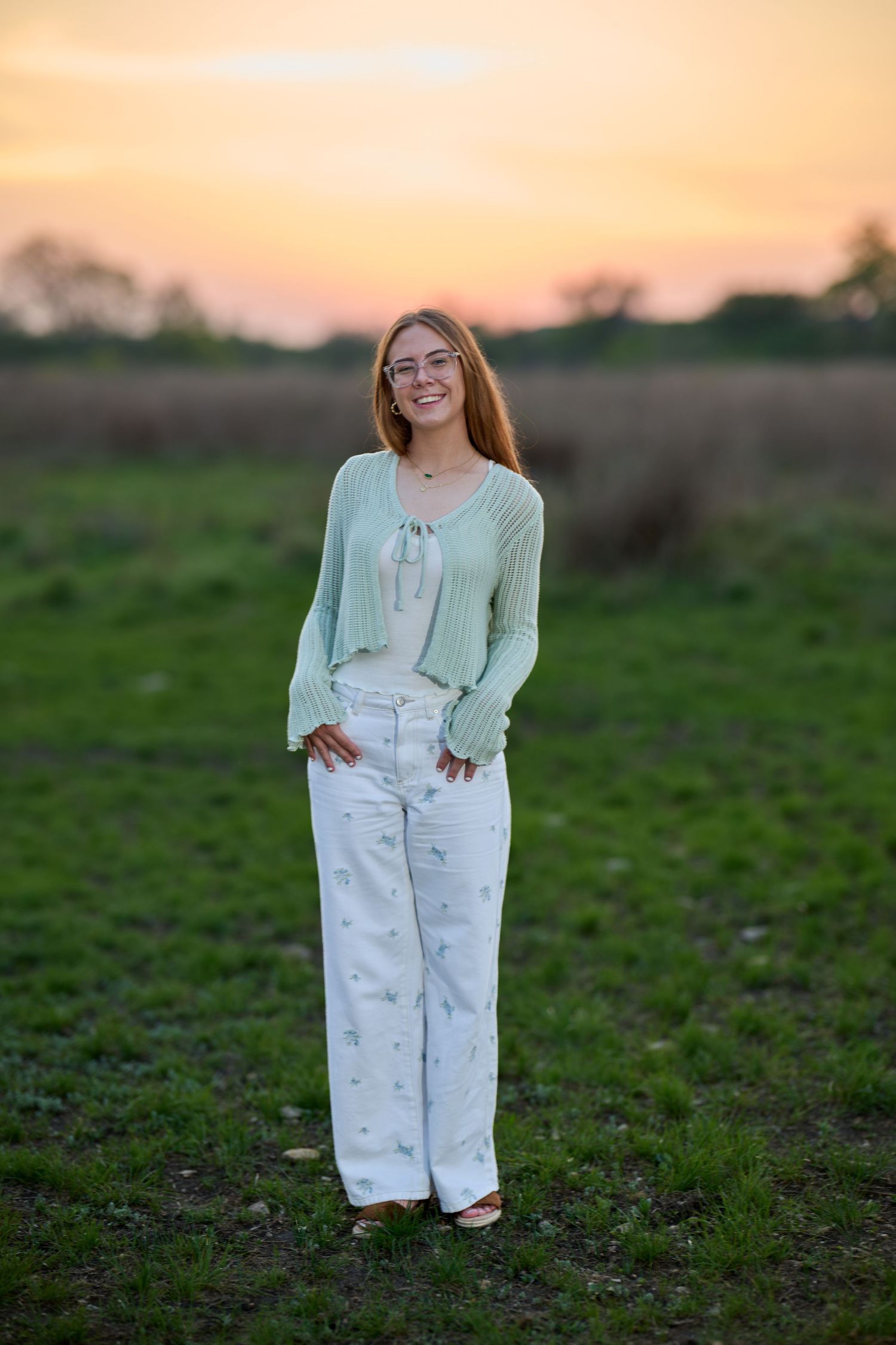 Portrait session in a field at golden hour showing casual white outfit against natural setting.