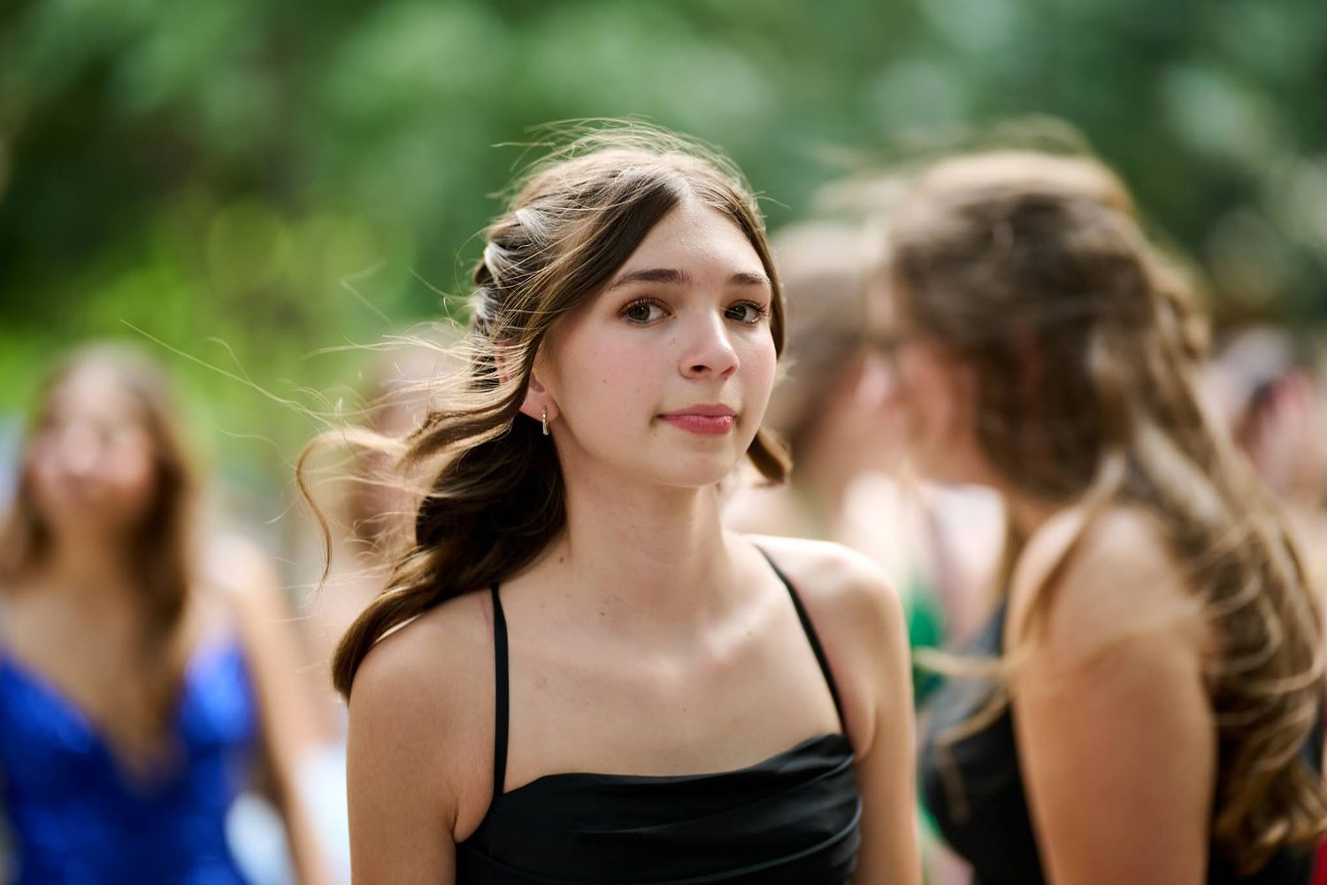 Candid shot of a young person in a black formal dress at an outdoor event.