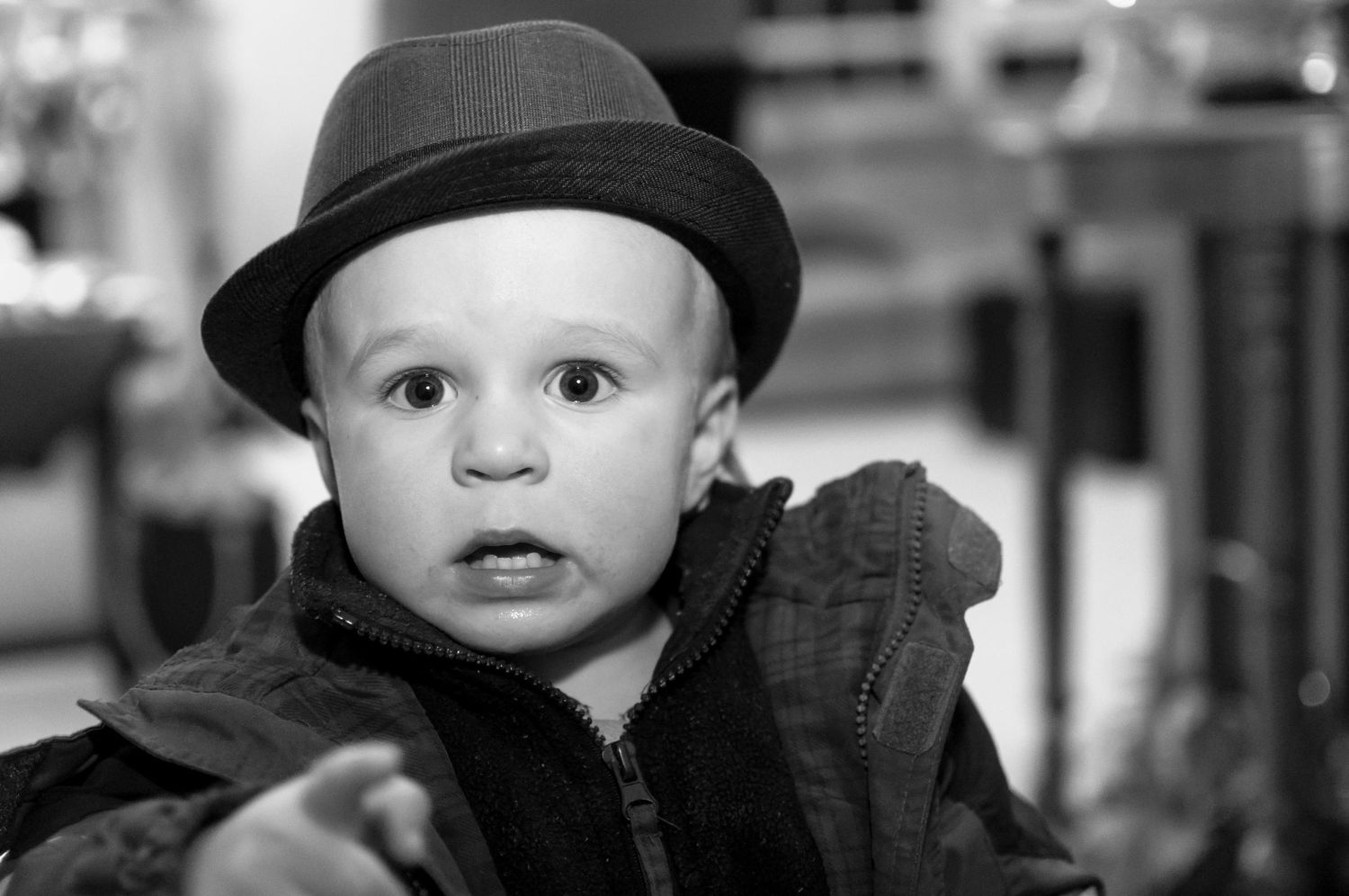 Black and white portrait of a toddler wearing a fedora hat and jacket.