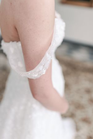 Close-up detail of delicate lace trim on a white wedding dress sleeve.