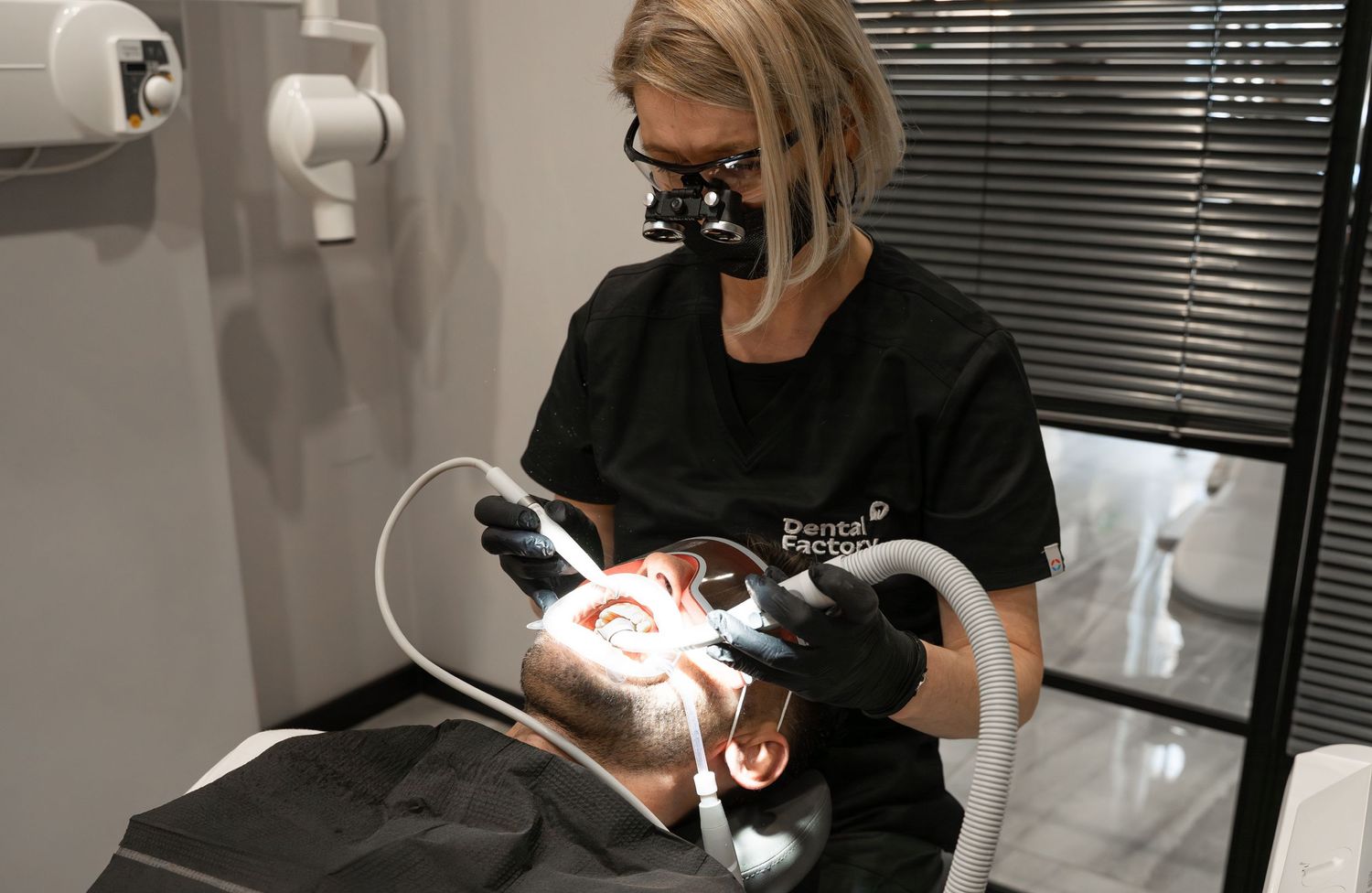 Dental professional performing procedure with specialized equipment in clinical setting.