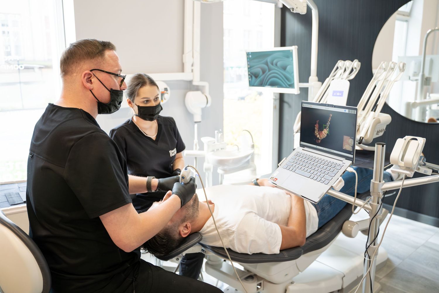 Dental professionals conducting patient examination with digital equipment in modern clinic.
