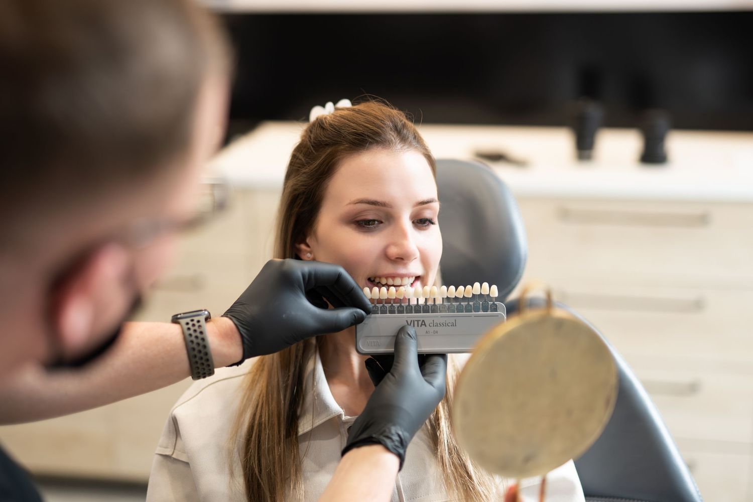 A dental examination being performed with a handheld mirror in a modern clinic setting.
