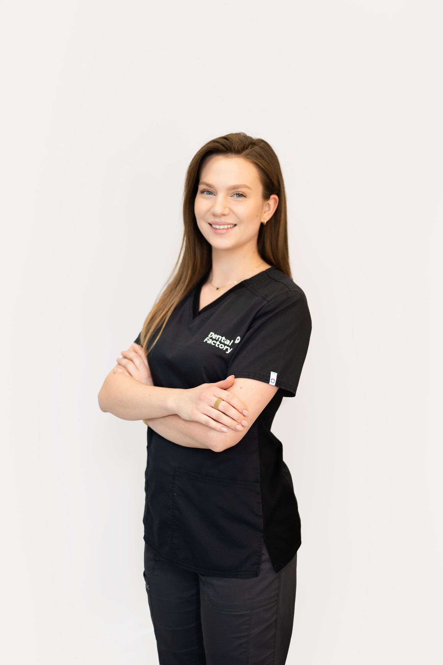 Healthcare professional in black scrubs standing confidently against white background.