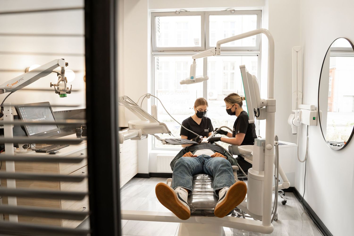 Modern dental office interior with equipment and treatment chair by bright windows.