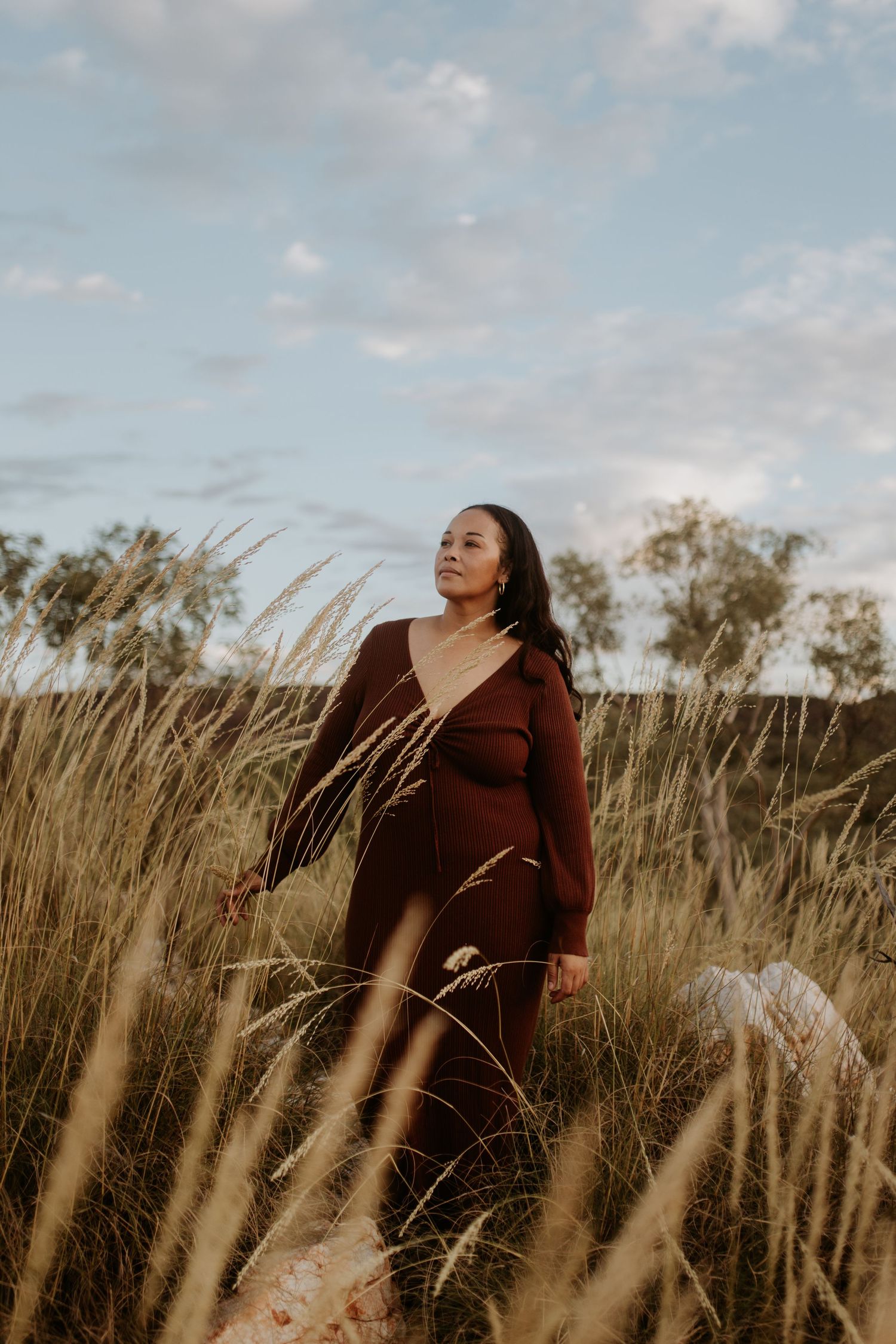 Woman poses amongst the long grass at Lake Moondarra during golden hour