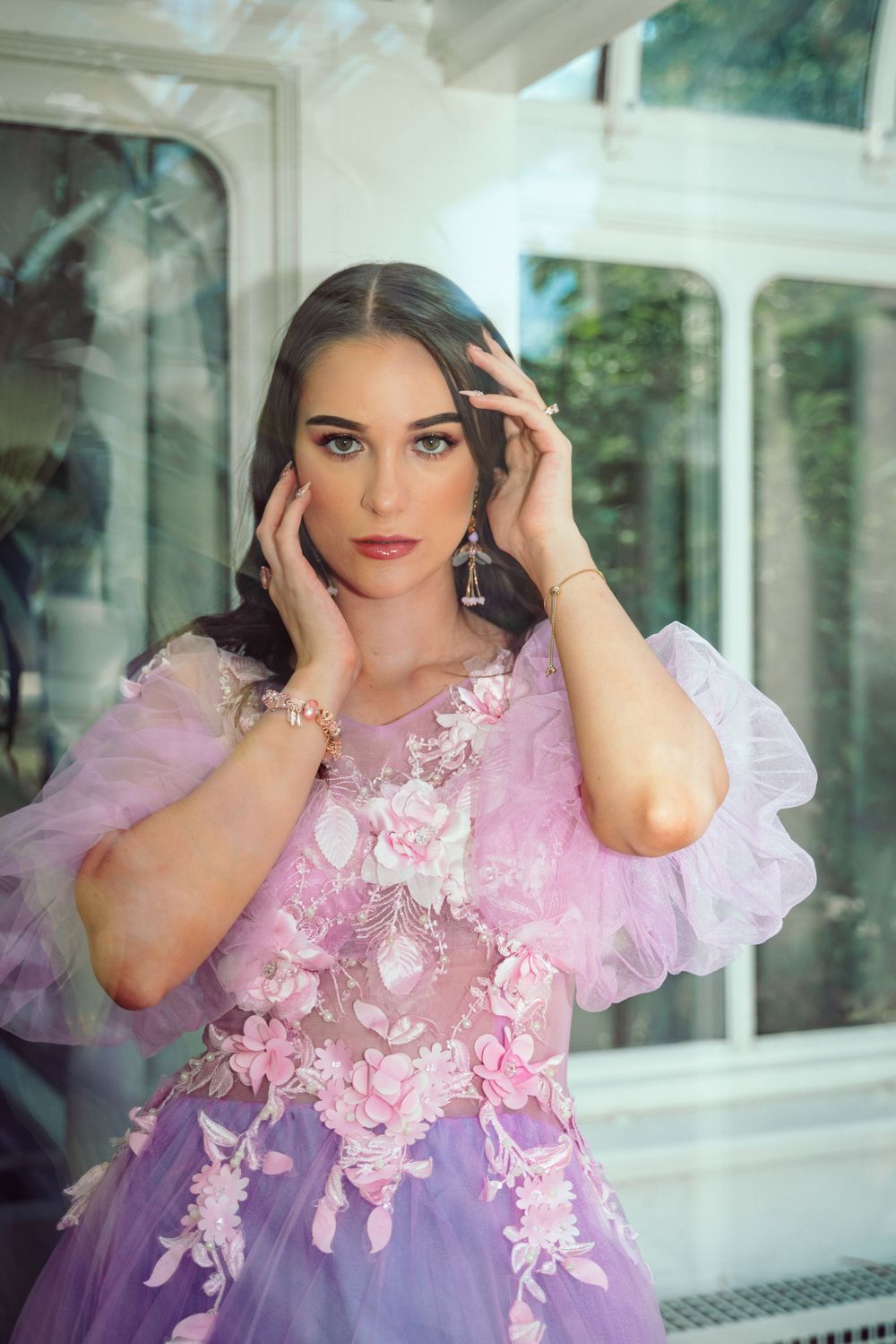Portrait in a flowing pink and purple floral gown near window light.