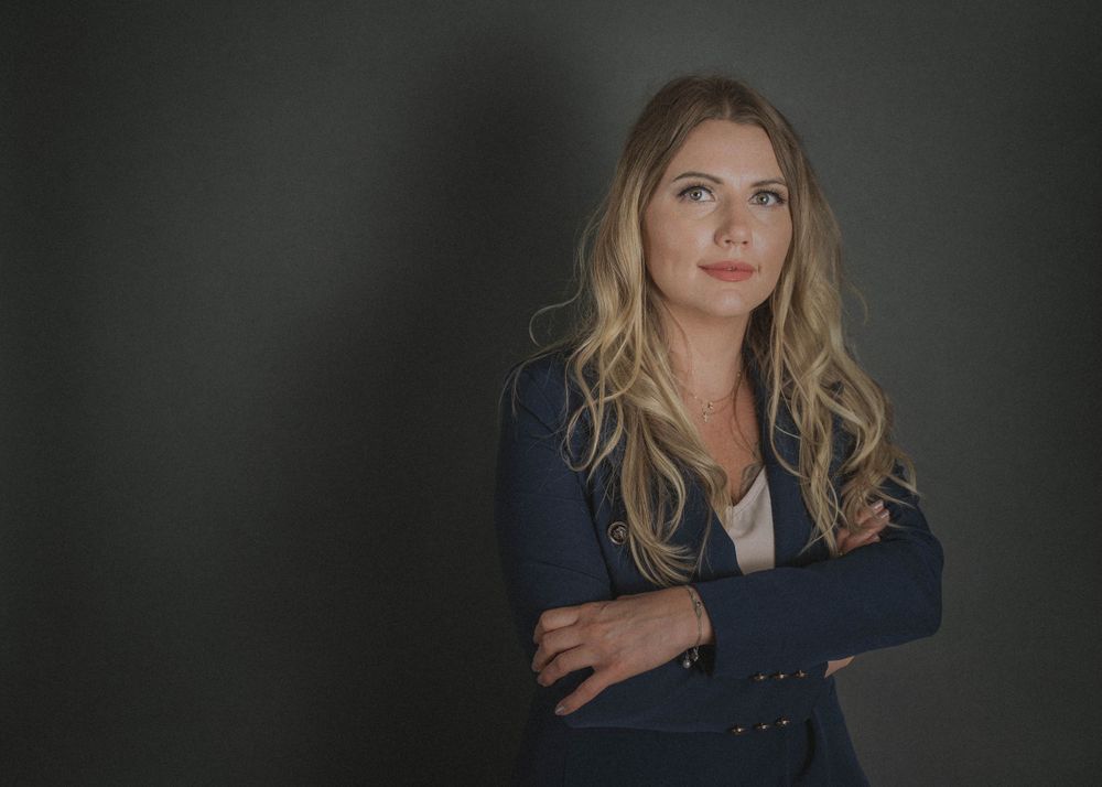 Professional studio portrait of woman in navy blazer against dark background.