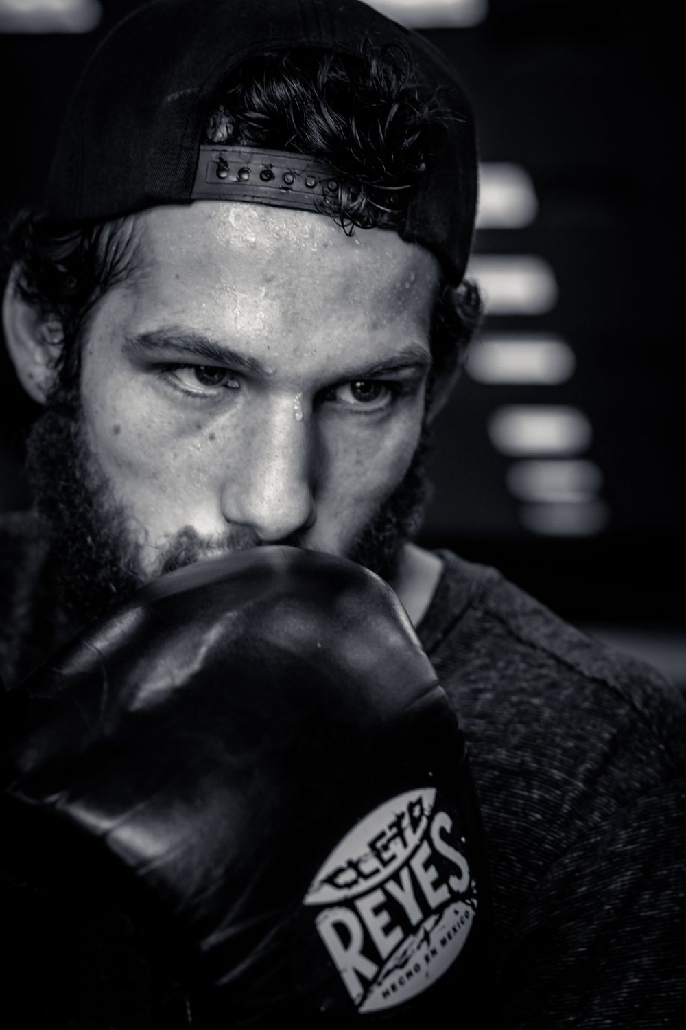 Dramatic black and white boxing portrait showing athlete with gloves in dark setting.