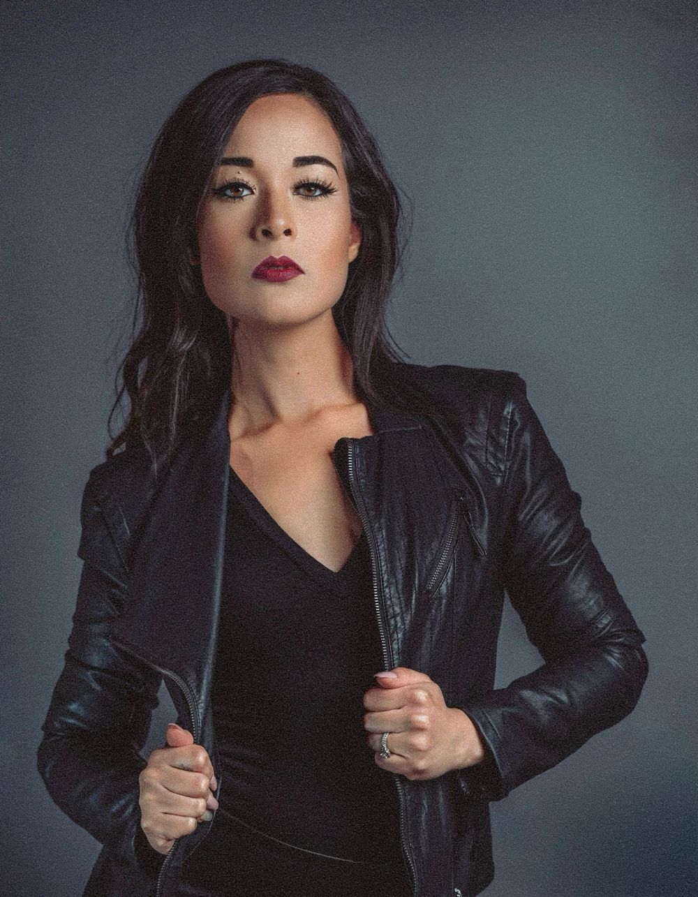 Dramatic portrait with black leather jacket against a moody studio backdrop.