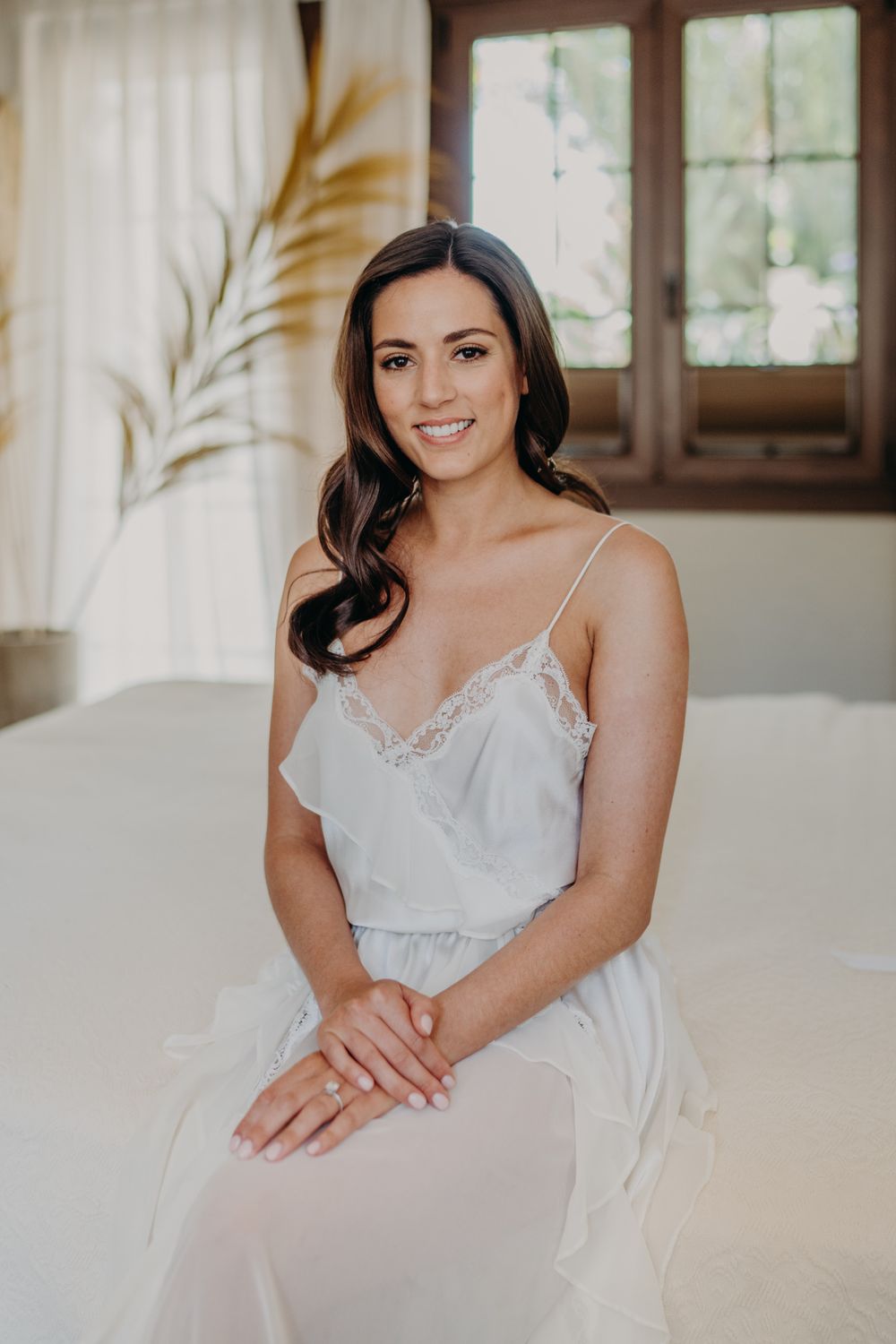 Ethereal white lace bridal robe shown in sunlit bedroom with palm decor.