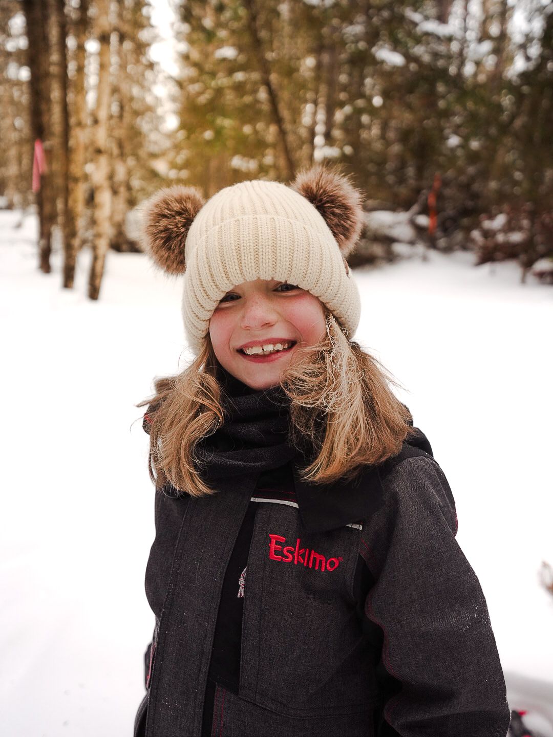 Winter portrait showing warm winter hats and cozy outerwear in snowy forest.