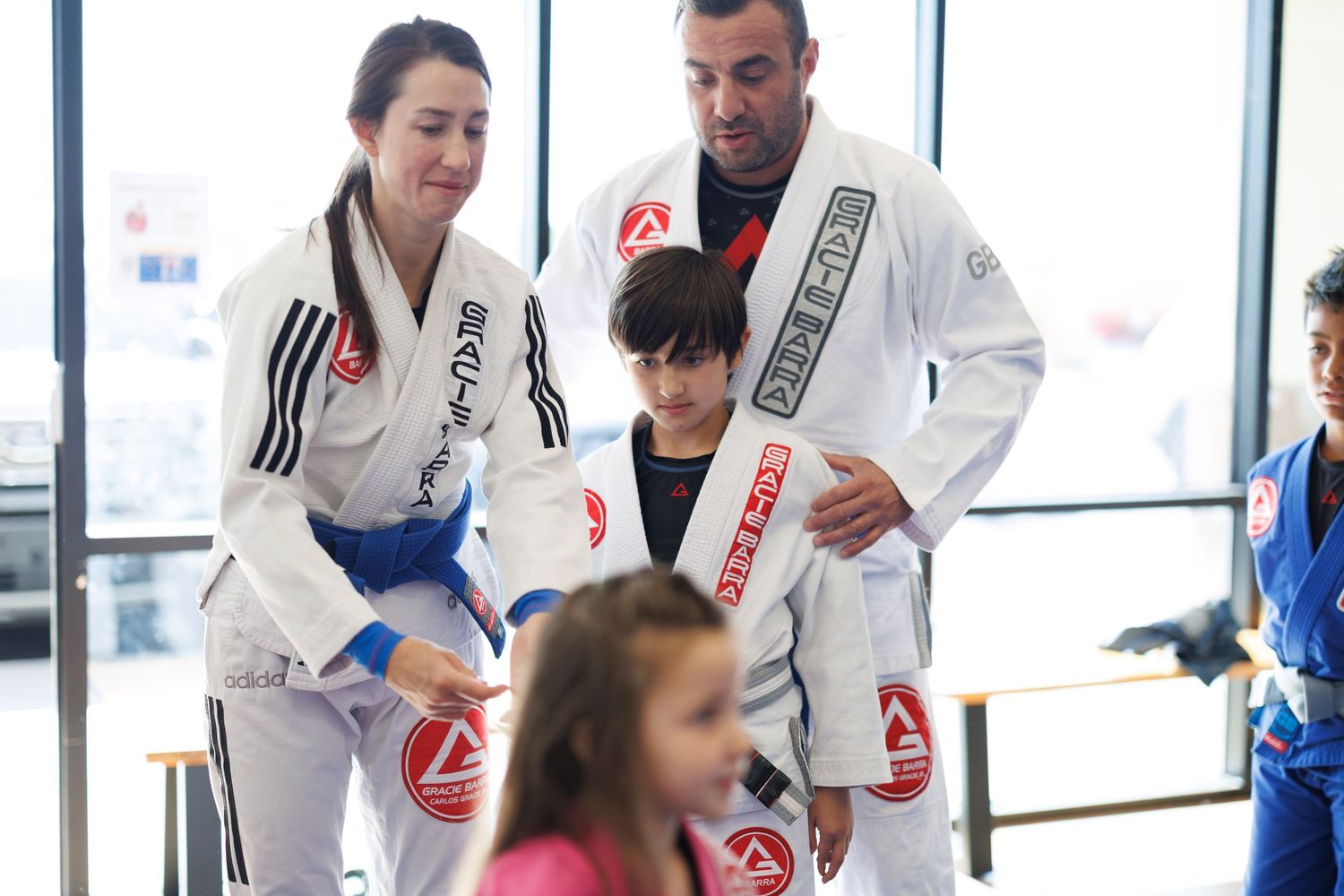 Martial arts family of practitioners in white gis training together in a bright studio space.