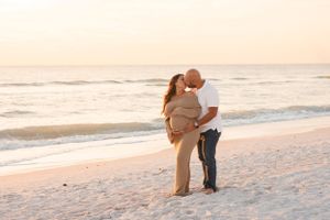 Silhouetted couple sharing intimate moment on beach at sunset.