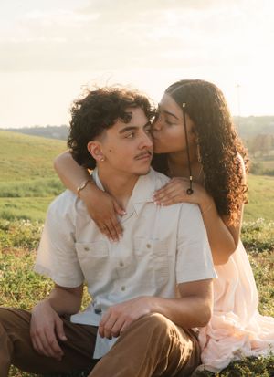 An intimate moment shared between a couple on a scenic hilltop during sunset.