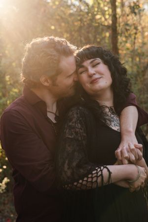 A tender embrace captured in golden sunlight filtering through autumn trees.