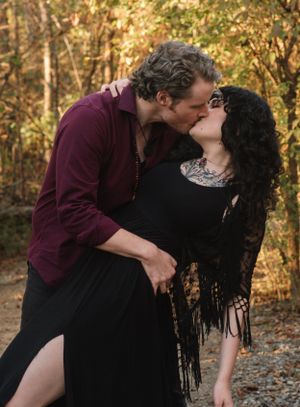 A romantic dip kiss moment captured in a forest setting during golden hour.
