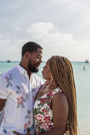 Romantic beach portrait with turquoise ocean and boats in the background.