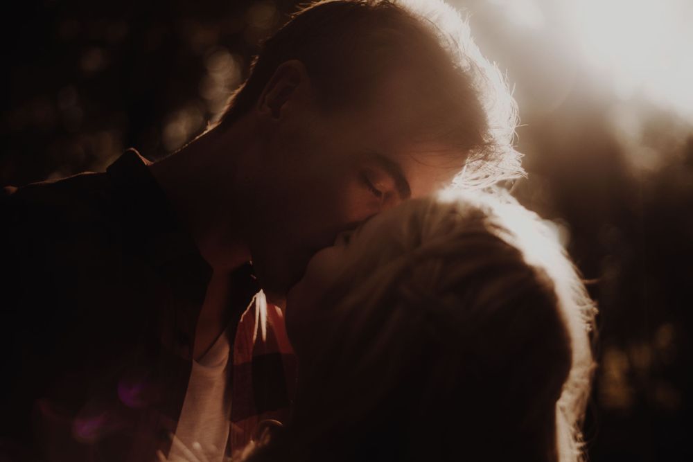 An intimate silhouette of two people sharing a romantic moment in golden backlight.