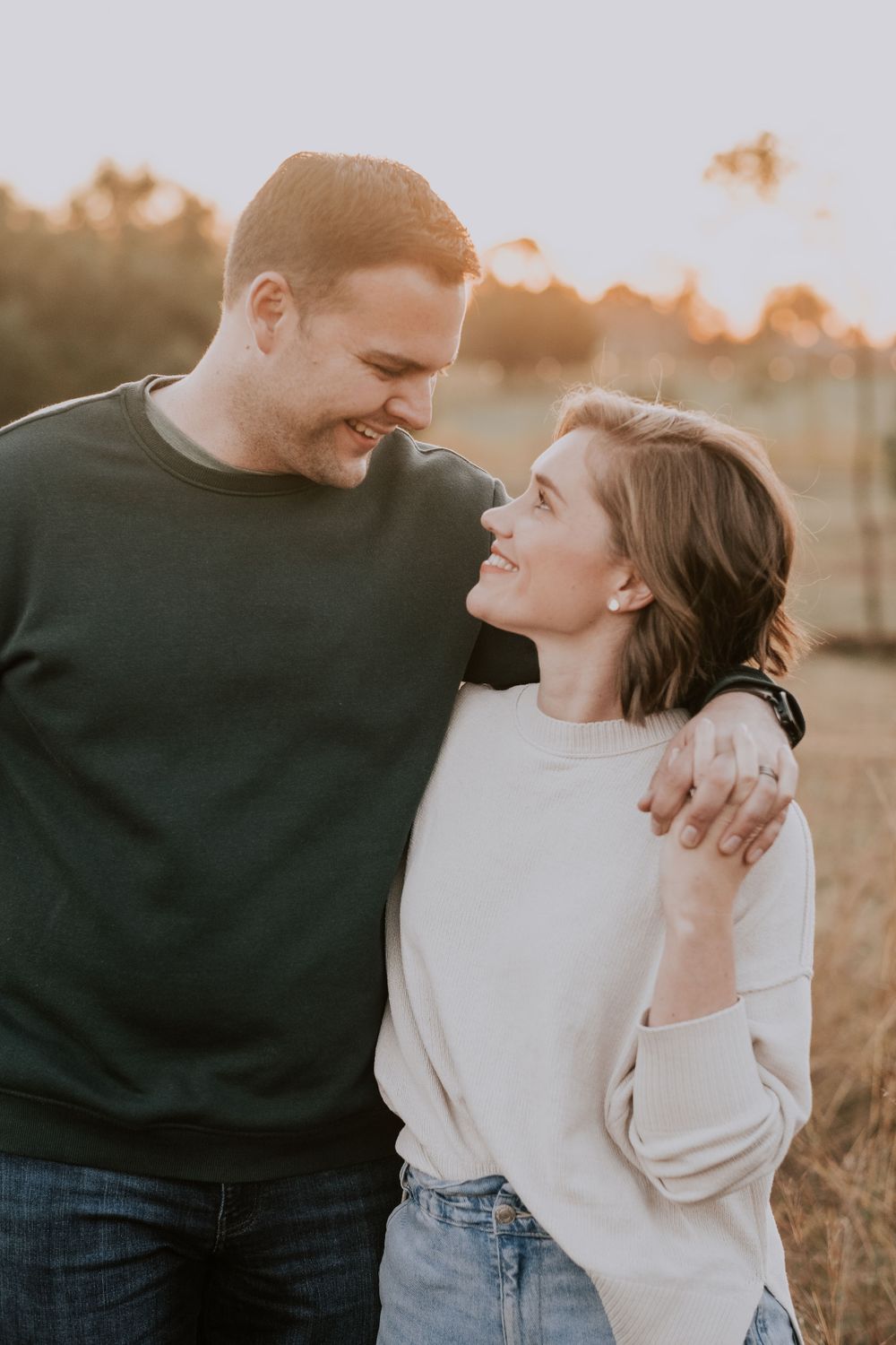 Couple sharing affectionate moment in casual wear during golden hour outdoors.