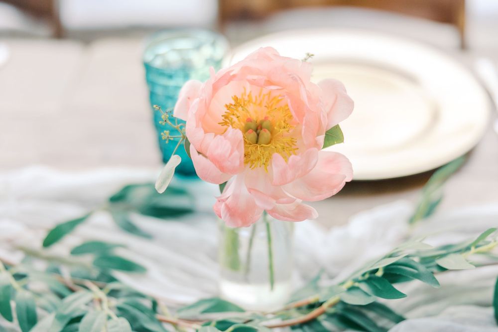 Delicate pink roses and greenery arranged as romantic wedding table decorations.