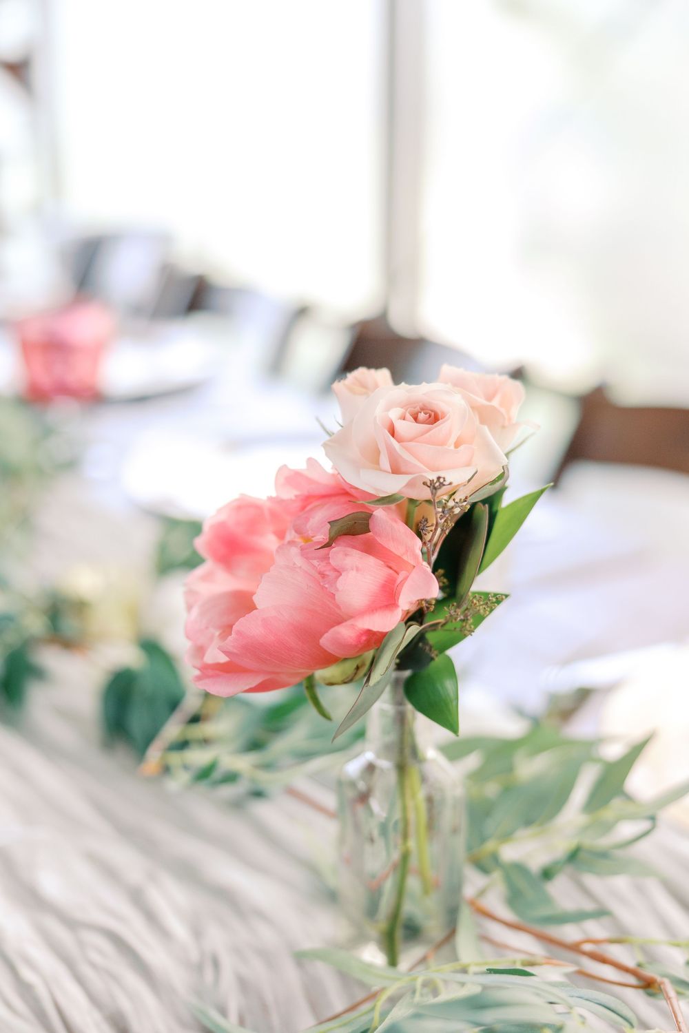 Soft pink roses with green foliage create an elegant tablescape arrangement.
