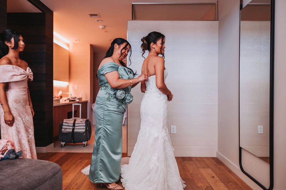 Wedding day preparation scene showing people in formal attire and white robes in a brightly lit room.