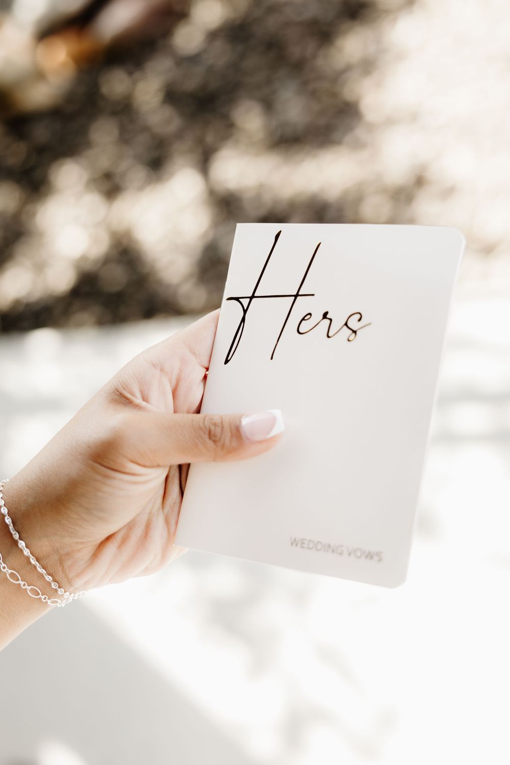 Hands holding wedding vows or letters against a soft white background.