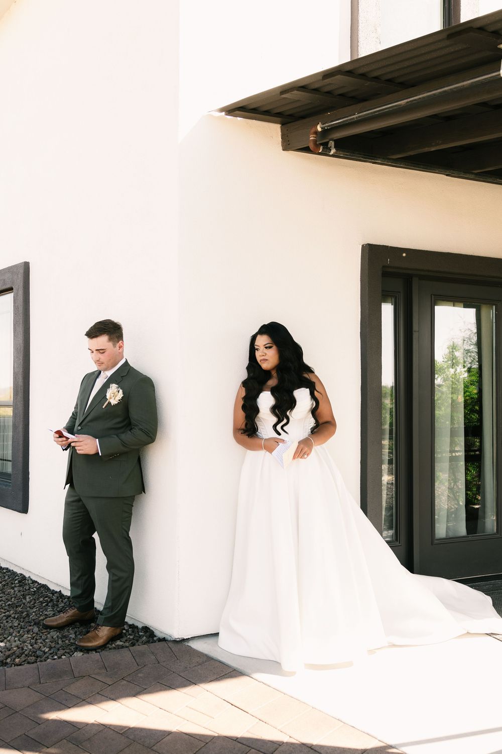 A couple playfully peek around corners during their first look wedding photos.
