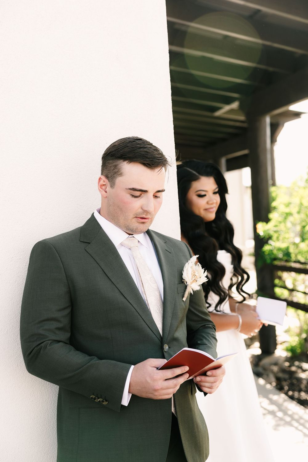 A couple reading from small books during their wedding ceremony on a porch.