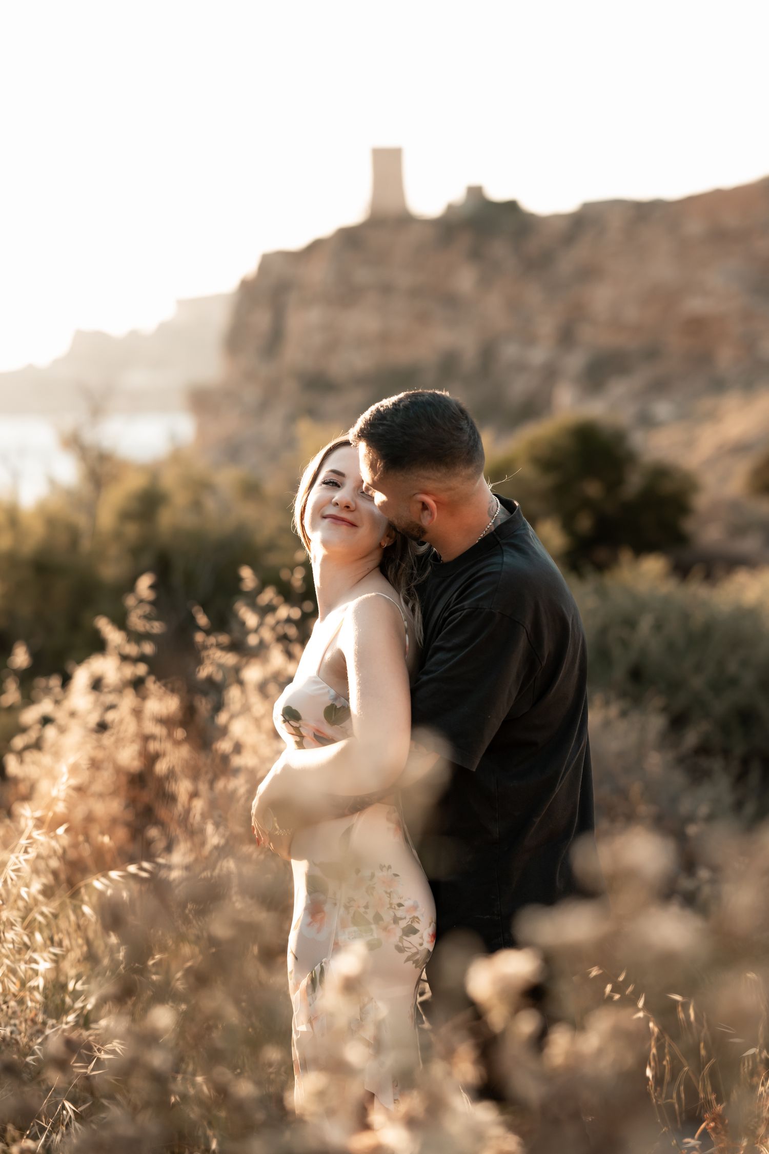 Couple embracing in a dreamy sunset setting with desert landscape.