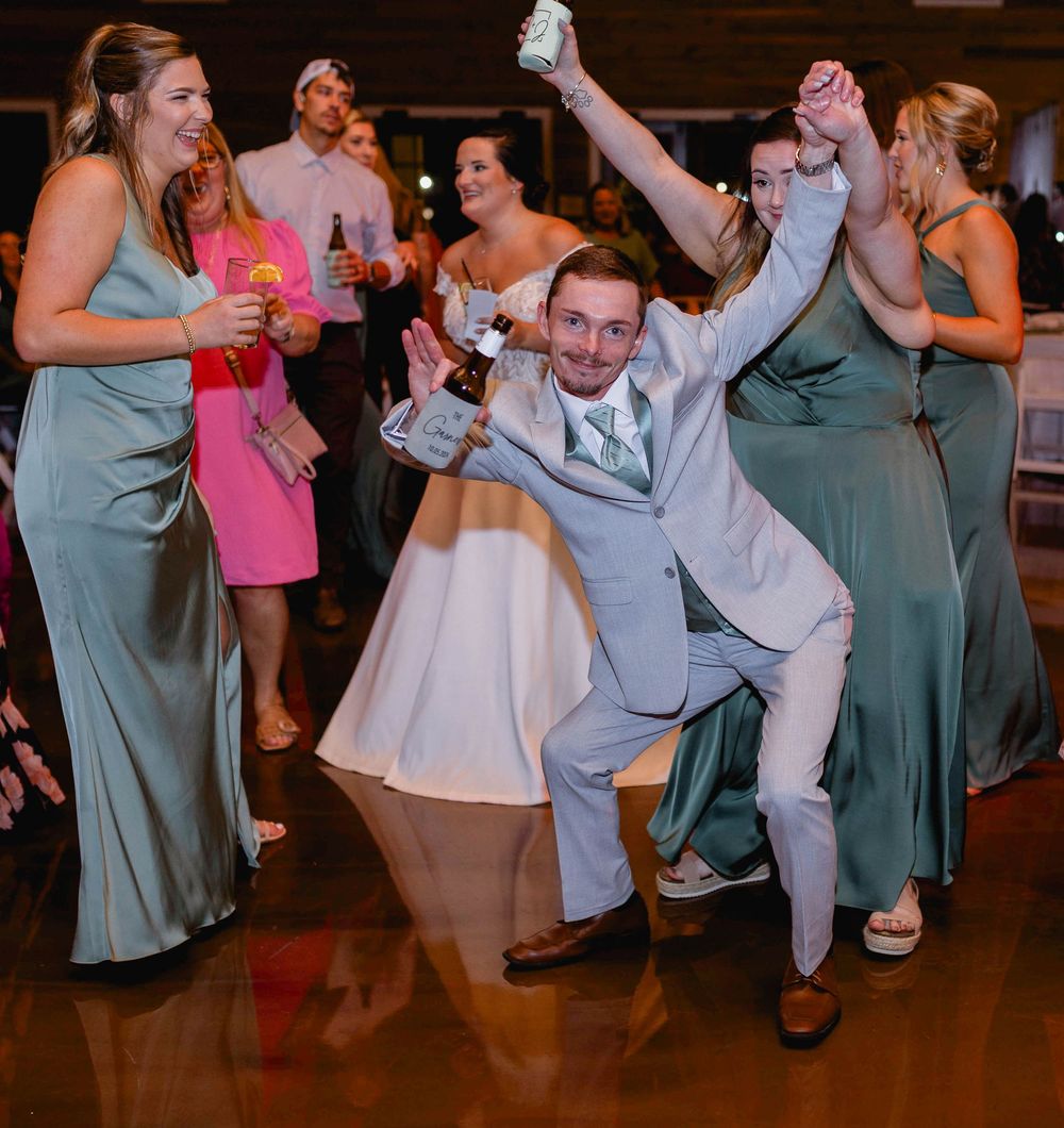 Wedding guests dance and celebrate energetically on a reception dance floor.