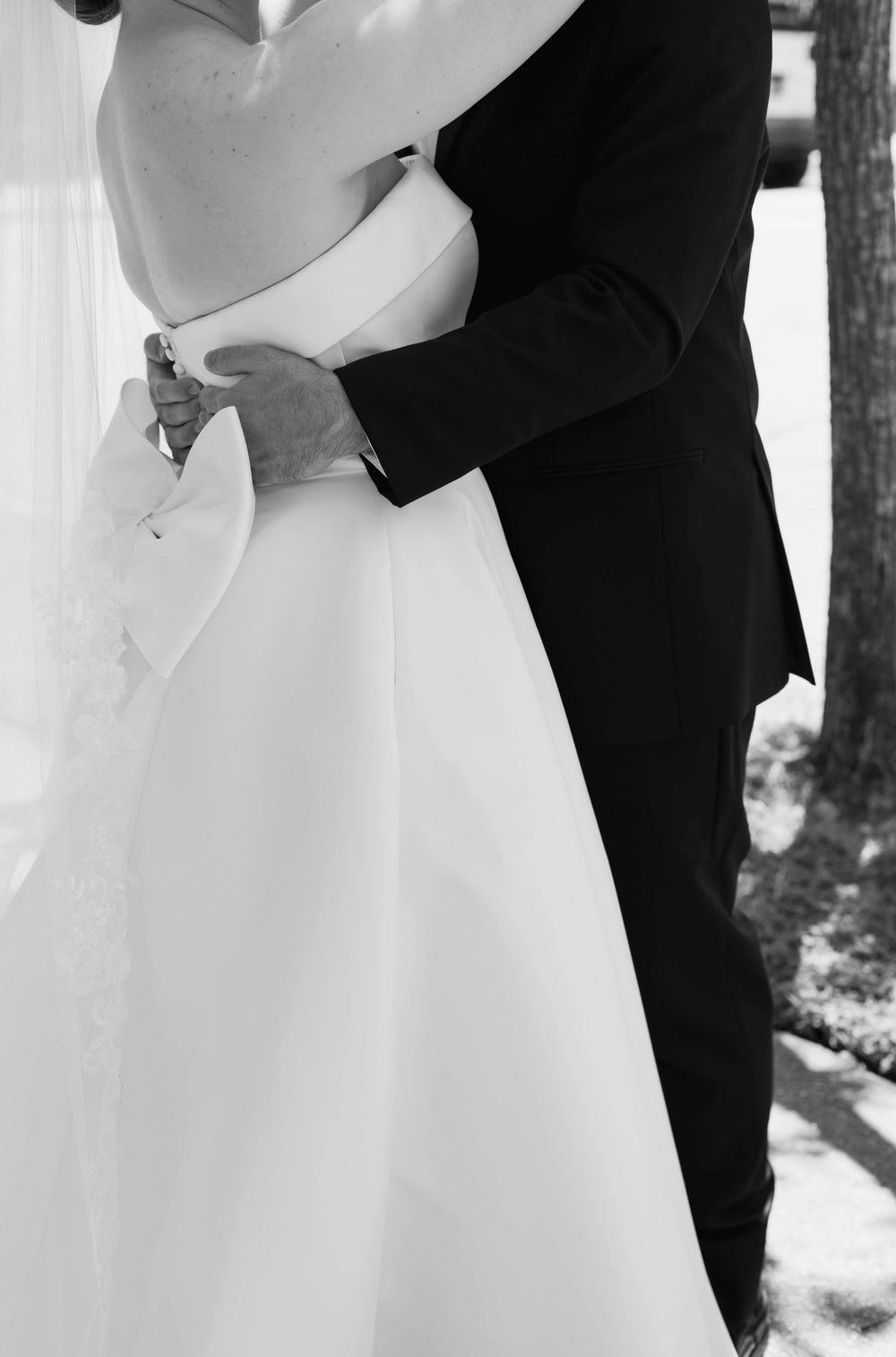 A romantic black and white portrait captures an intimate wedding moment outdoors.