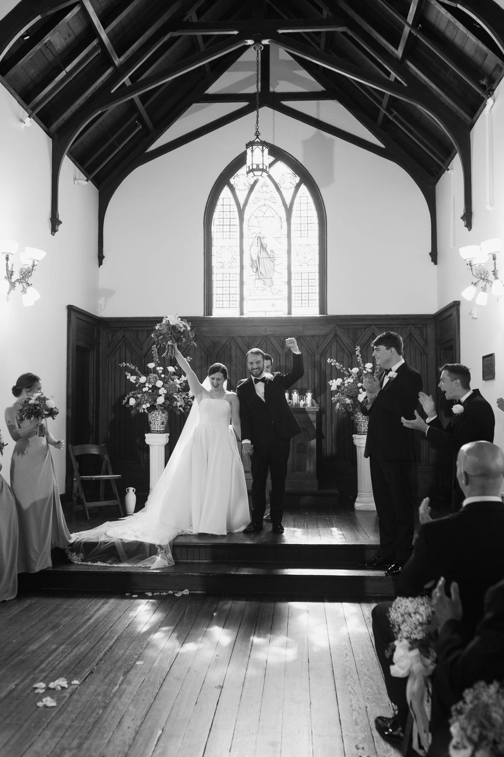 Black and white photos showing a wedding ceremony in a traditional church with wooden beams and stained glass windows.