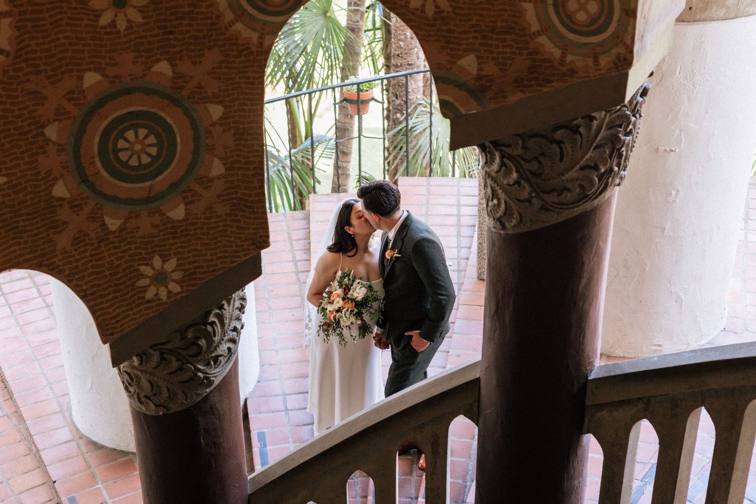 Newlywed cute couple posing under tiled archway at the courthouse.
