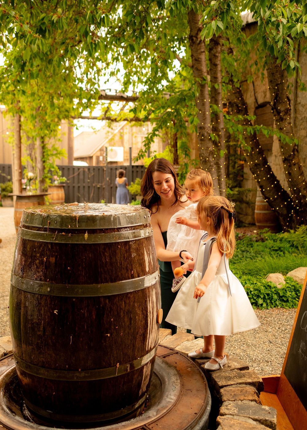 A sweet moment by a rustic wooden barrel in a garden setting.