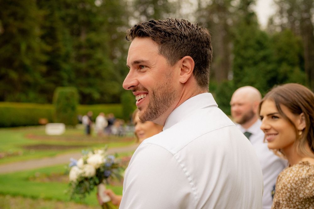 Happy couple shares joyful moment at outdoor wedding ceremony in a garden setting.